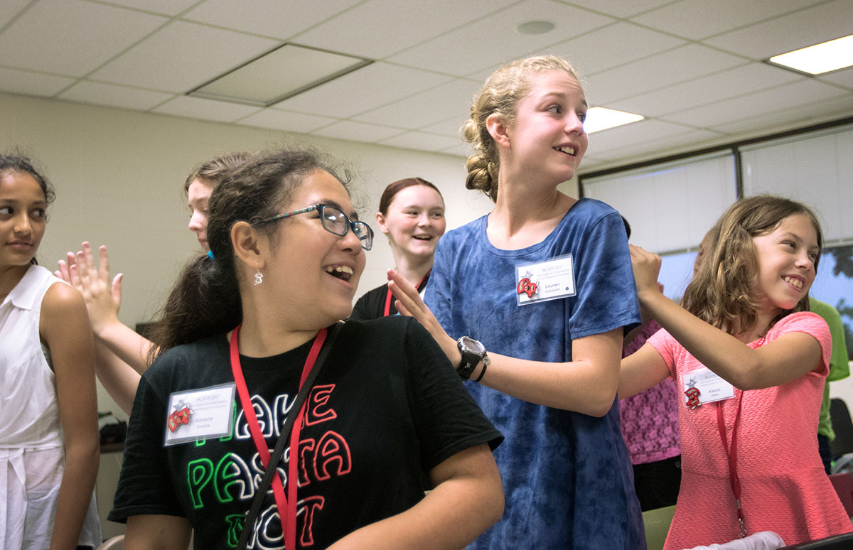 Annora Striegle (from left) of Charlotte, N.C., Lauren Goldsmith of Bowling Green, and Alecia Glenn of Bowling Green form a massage train in Singing 101 Thursday, June 15. Massages are part of the daily warm-up  routine for the class before they begin singing. (Photo by Brook Joyner)
