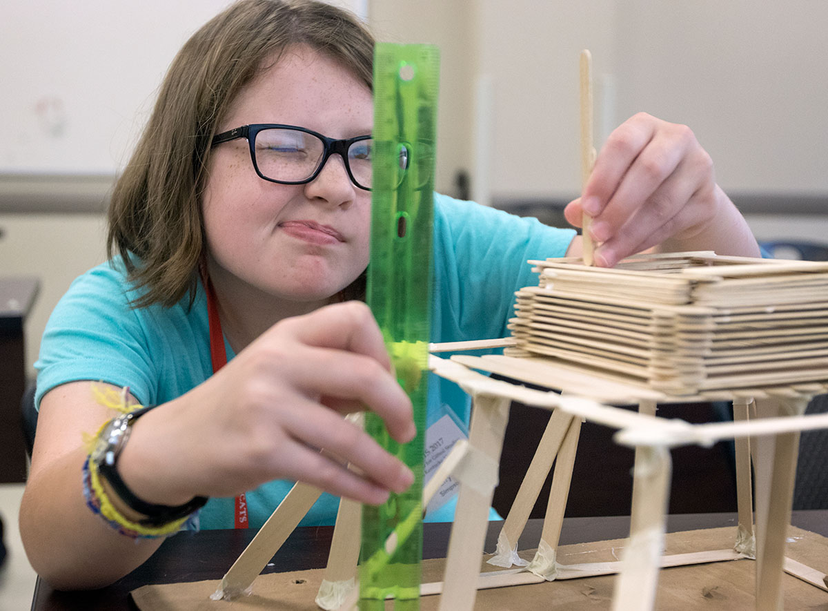 Lily Simpson of Bowling Green measures the height of her popsicle stick structure in Shake, Rattle, and Roll Thursday, June 22. The class was challenged to build a structure that would be able to hold a water bottle and remain standing when put on a shake table. (Photo by Brook Joyner)