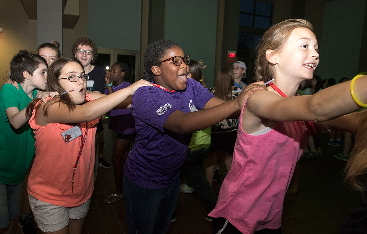 Alli Wagner (from left) of Leitchfield, Kayla Wood of Horse Cave, and Hayden Tichenor of Henderson dance in a conga line at the SCATS dance Thursday, June 22. Campers celebrated the last night of camp with a banquet, dance, and slideshow. (Photo by Brook Joyner)