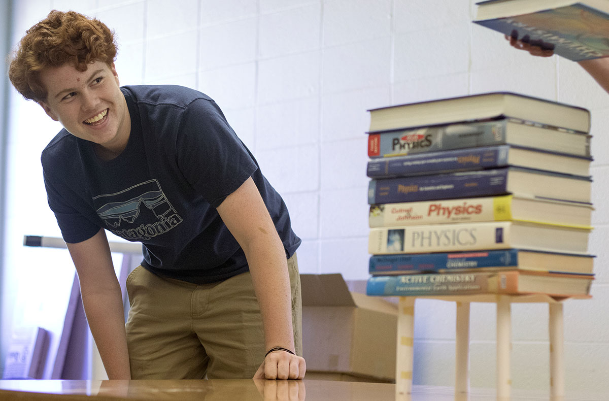 Tommy Pack of Frankfort watches as his classmate stacks books on top of their paper structure in Problems You've Never Solved Before Monday, June 26. The class competed to see whose design could hold the most books using only paper and tape. (Photo by Brook Joyner)