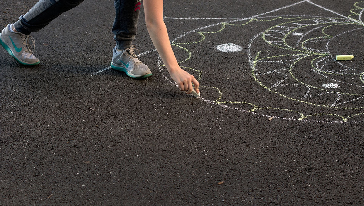 Elizabeth Rexroat of Columbia draws with sidewalk chalk in front of Florence Schneider Hall Tuesday, June 27. Each evening, campers participate in optionals, giving them the opportunity to try out a variety of activities. (Photo by Brook Joyner)