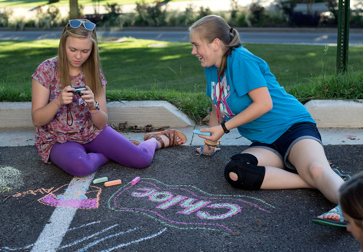 Bailey Richardson (left) and Chloe Cox, both from Clarkson, look at pictures on Bailey's camera during optionals Tuesday, June 27. Since campers aren't allowed to have phones, many bring digital cameras with them to take pictures. (Photo by Brook Joyner)