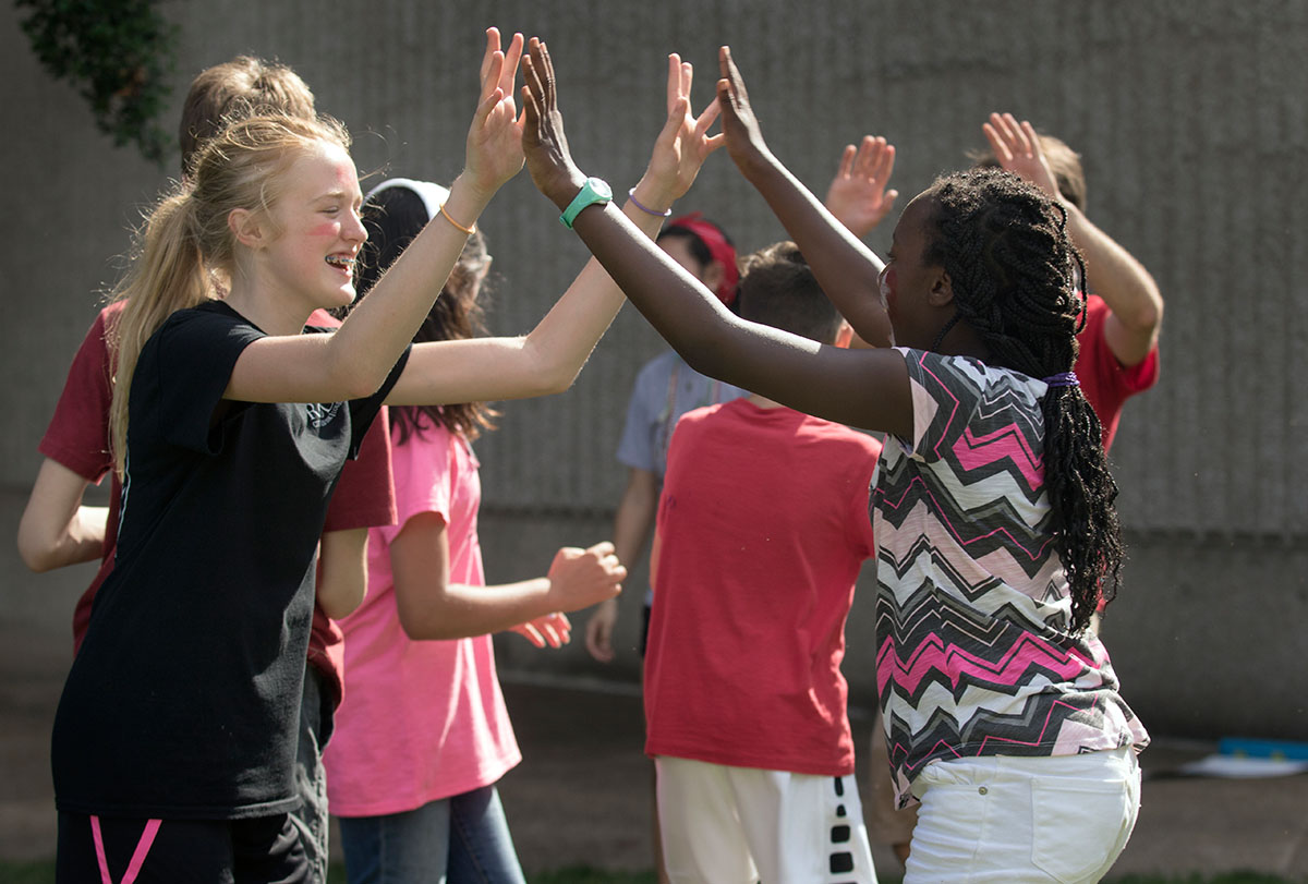 Laurel Wallace (left) of Louisville and Nyomi Drayton of Franklin high-five after finishing the final event of SCATS Olympics Saturday, June 17. Teams had to compete in a relay race involving trays of whipped cream, a word search, and water balloons. (Photo by Brook Joyner)