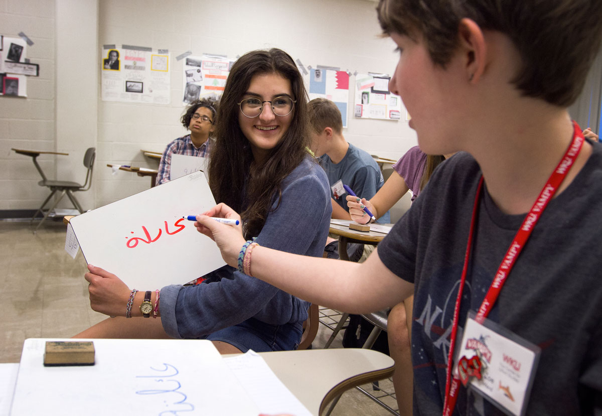 Martha Popescu (left) from Hanson shows her white board to Zoe Ward of Frankfort to get feedback on how she wrote her name during Arabic Monday, July 3. (Photo by Sam Oldenburg)