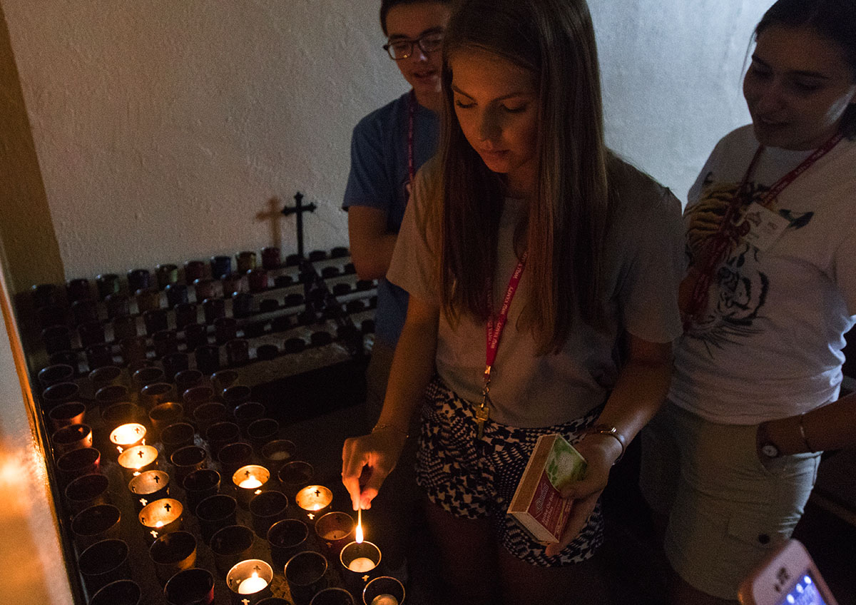 Lauren Simons of London lights a candle at the altar of Monte Cassino Shrine while on a Humanities field trip to St. Meinrad, Ind. Monday, July 3. (Photo by Brook Joyner)