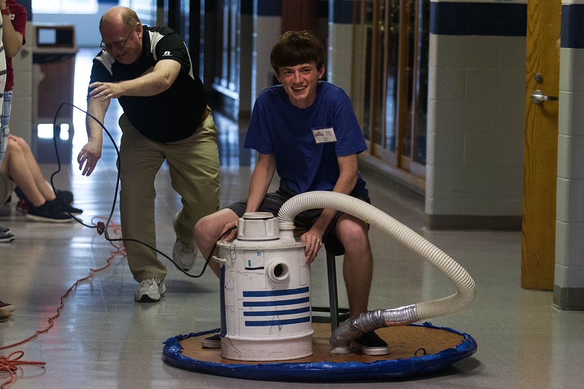 Physics teacher Kenny Lee pushes Jared Rogers of Verona down the hallway on a homemade hover craft Wednesday, July 12. Each student took a turn gliding down the hall for the final demonstration of the Physics field trip to Warren Central High School. (Photo by Brook Joyner)