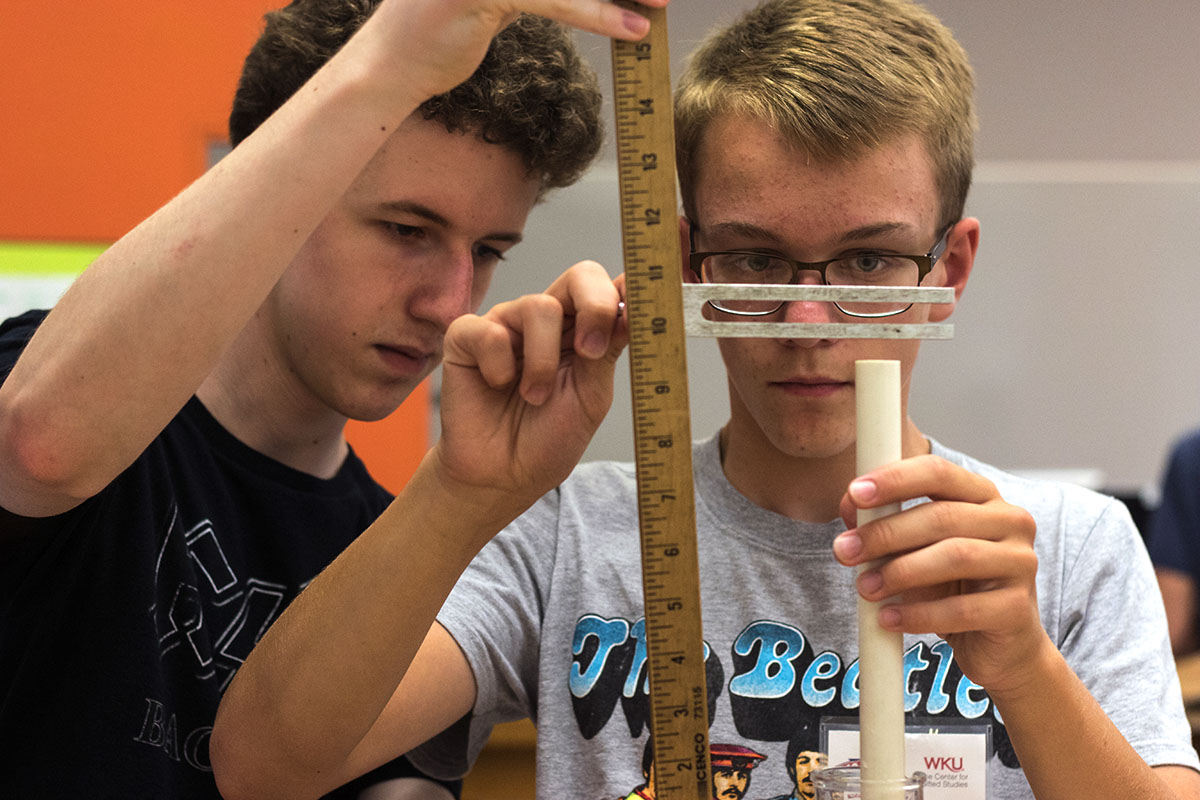 Patrick O'Boyle of Elizabethtown and Sam McGuire of Boonvile, Ind. complete a lab in Physics Monday, July 10. Using a tuning fork, PVC pipe, and a graduated cylinder full of water, students were able to find the natural resonance and amplify the sound from the tuning fork. (Photo by Brook Joyner)