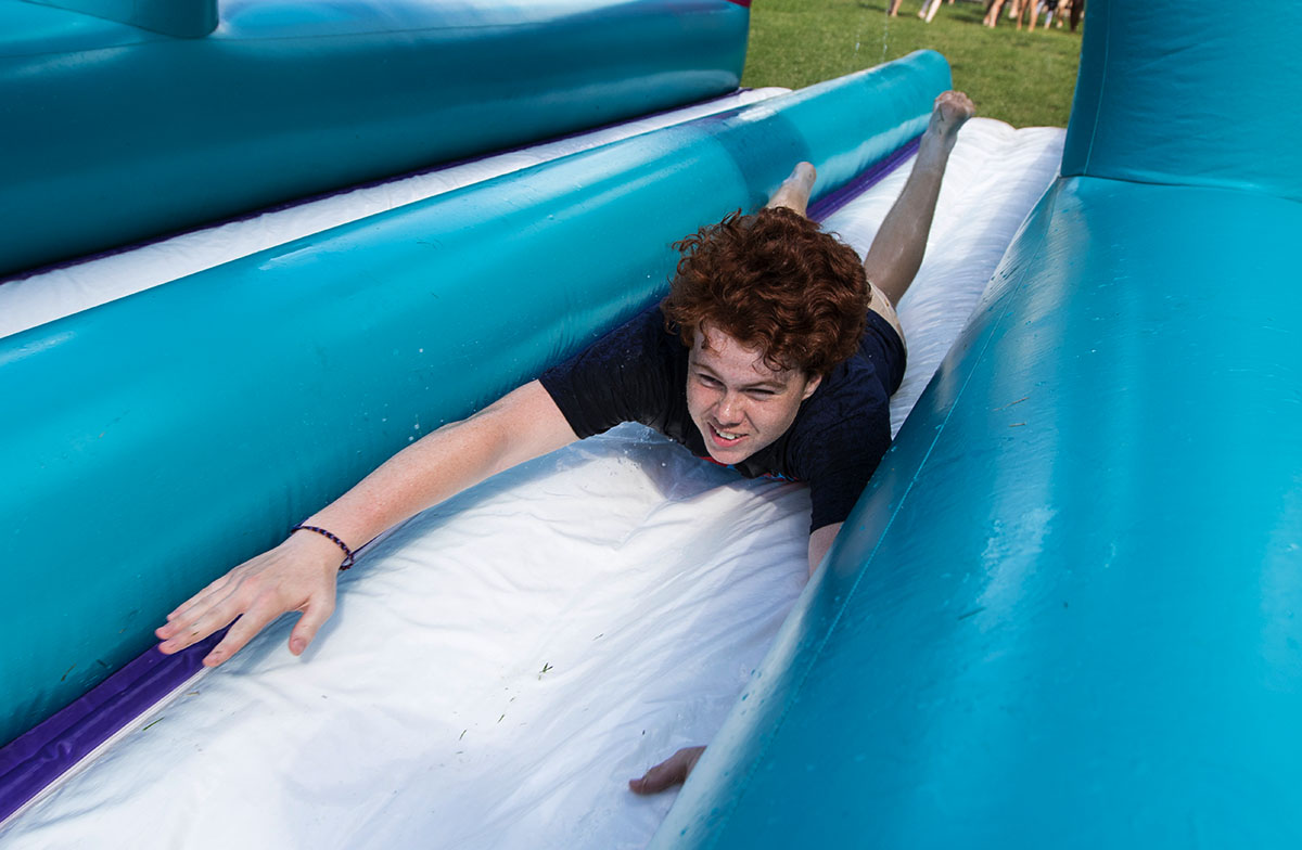 Tommy Pack of Frankfort glides down the giant slip n' slide after the final day of classes Friday, July 14. Traditionally, campers run through a fountain on their last day, but it was under construction. (Photo by Brook Joyner)