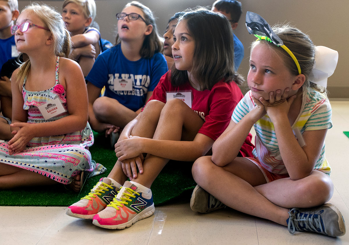 Claire Ellington (middle) and Ainsley Schmidt (right) listen as Math teacher Allison Bemis reads a story to the class Monday, July 10. Students then participated in a series of activities to learn about probability and chance. (Photo by Brook Joyner)