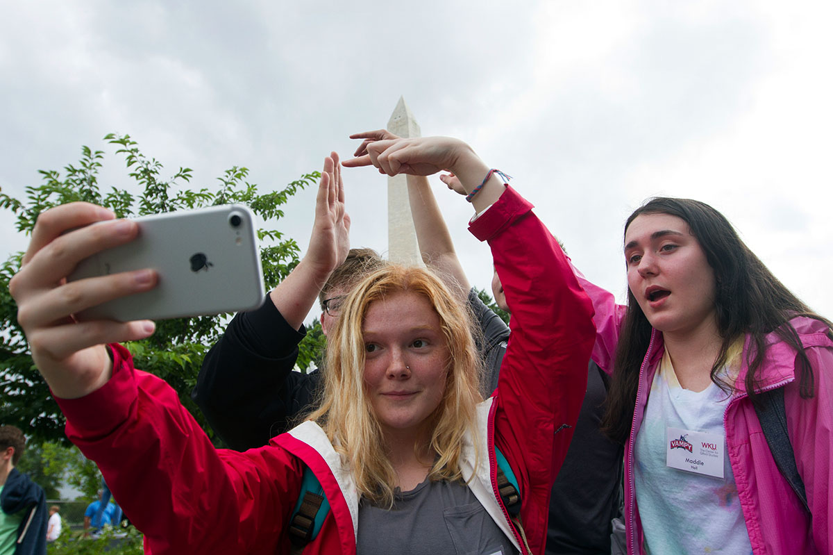 Sarah Ball (left) from Louisville, Maddie Hall from The Plains, Ohio, and other students try to take a selfie that gives the illusion of touching the Washington Monument during a field trip to Washington D.C. Thursday, July 6. (Photo by Sam Oldenburg)