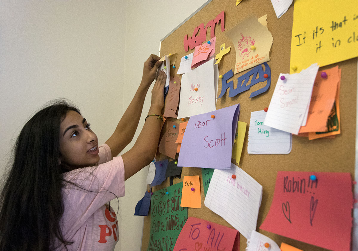 Hannah Jawed of Corbin pins "warm and fuzzies" on the bulletin board in the Florence Schneider lobby before going to dinner Sunday, July 2. Thie board is a place for campers and counselors to leave nice, encouraging notes for one another. (Photo by Brook Joyner)